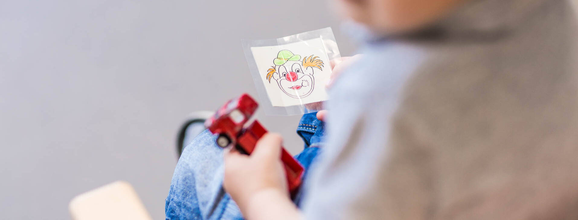 Ein Kind hat ein Bild von einem Clow in der Hand