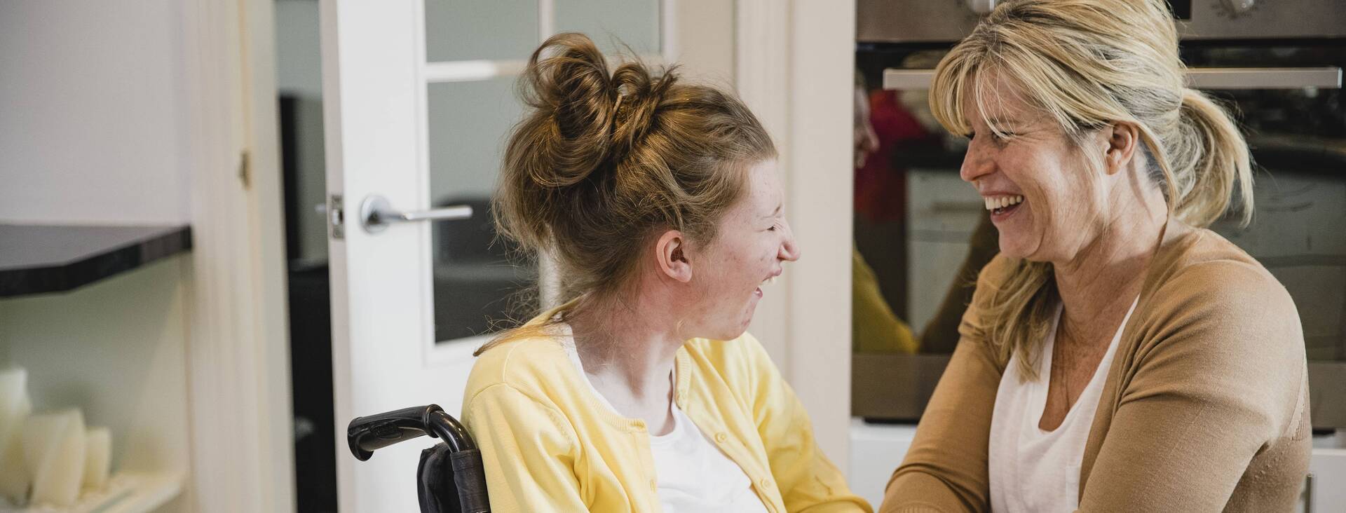 Eine Betreuerin spricht mit einer Frau im Rollstuhl