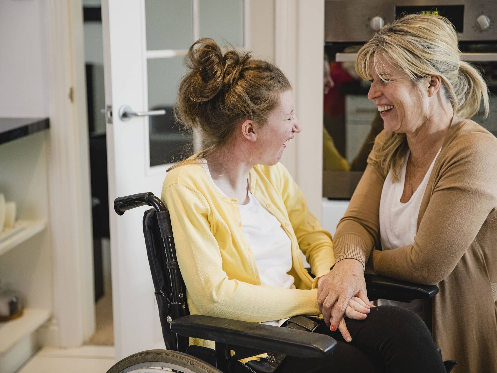 Eine Betreuerin spricht mit einer jungen Frau im Rollstuhl