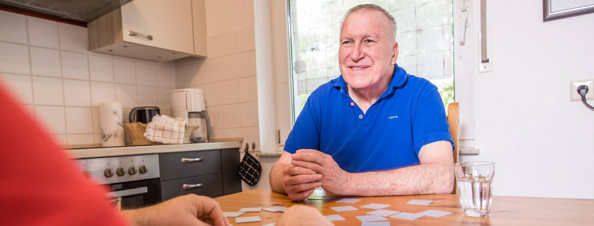 Alter Mann wird beim Kartenspielen gezeigt, und lächelt fröhlich.