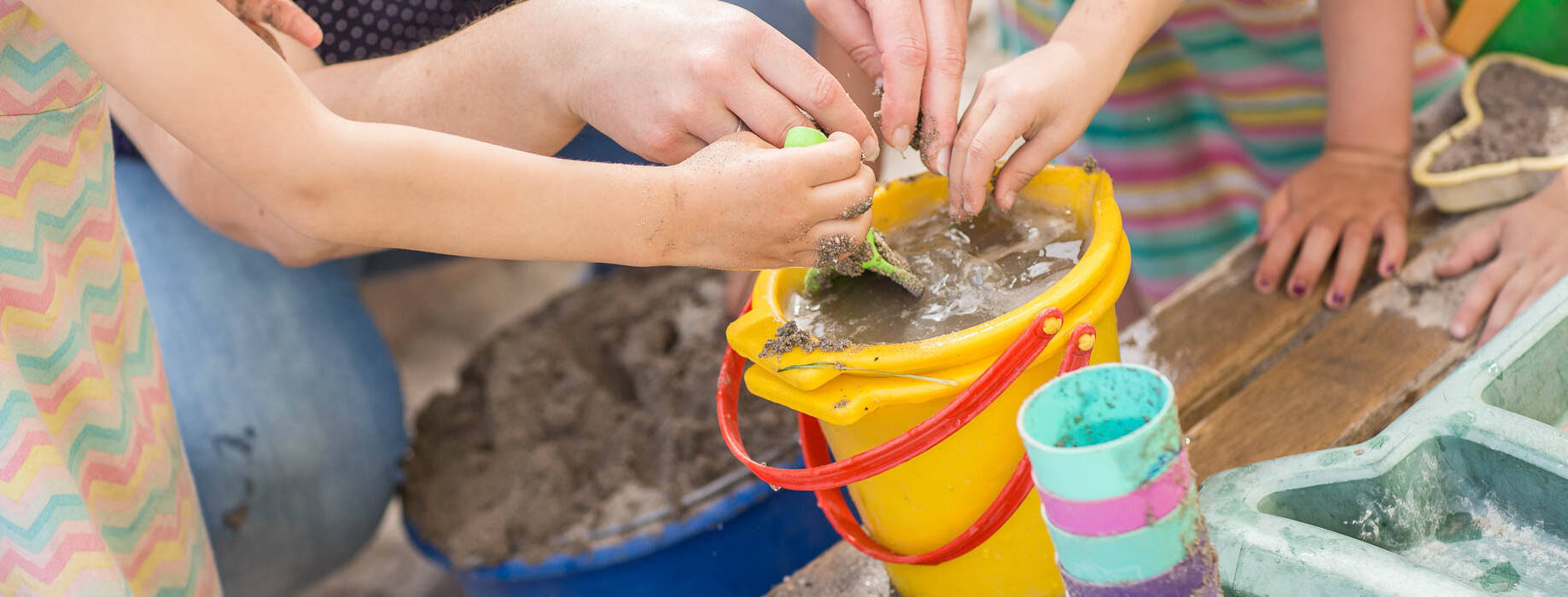 Kinderhände spielen mit Wasser und Sand
