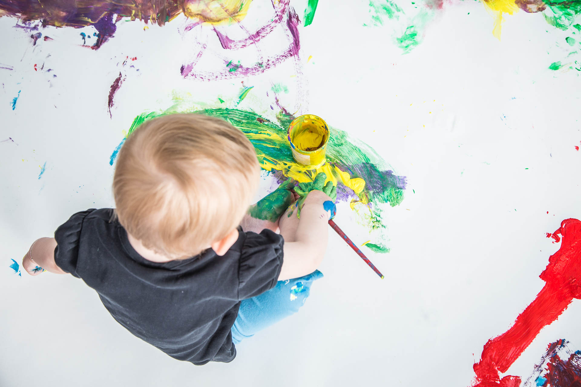 ein kleiner Junge malt mit Pinsel und Farben